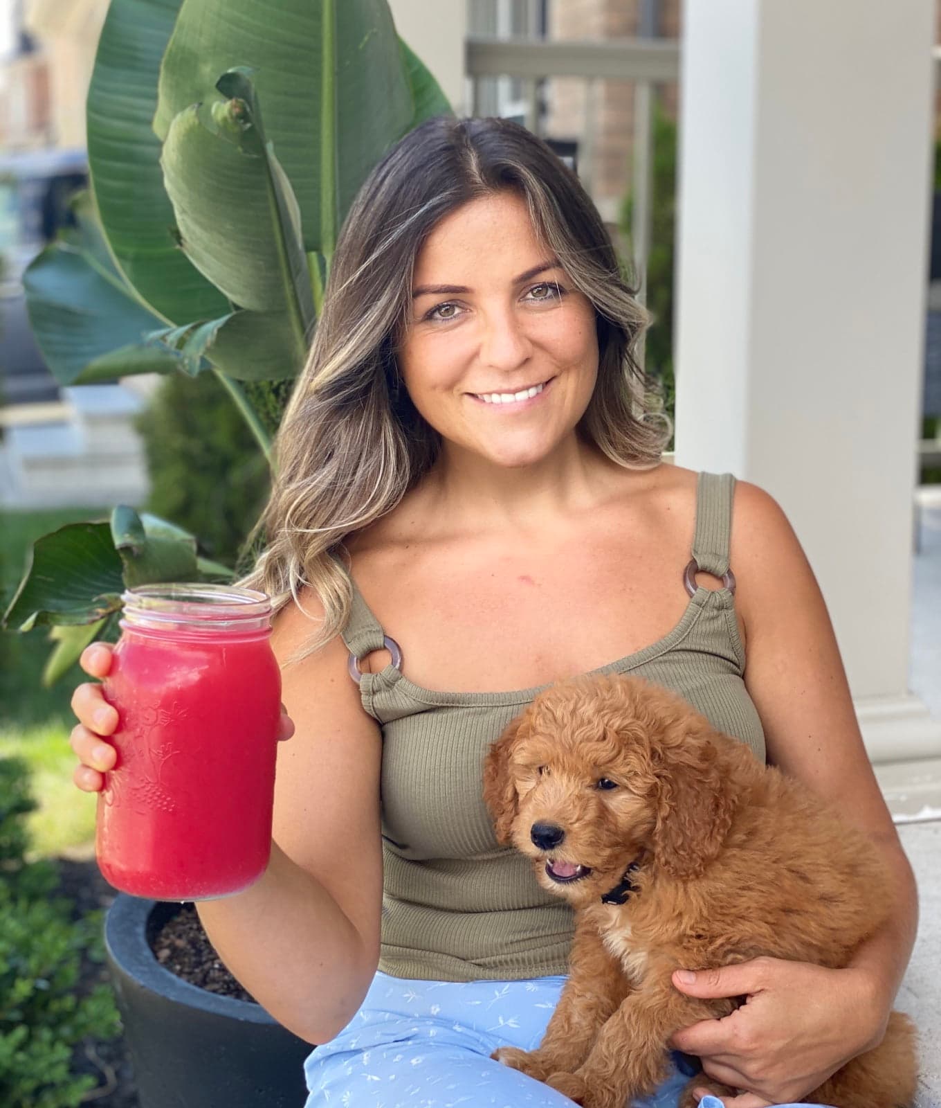 Ivonka of JuiceMadam holding a jar of fresh watermelon juice, with her puppy on her lap