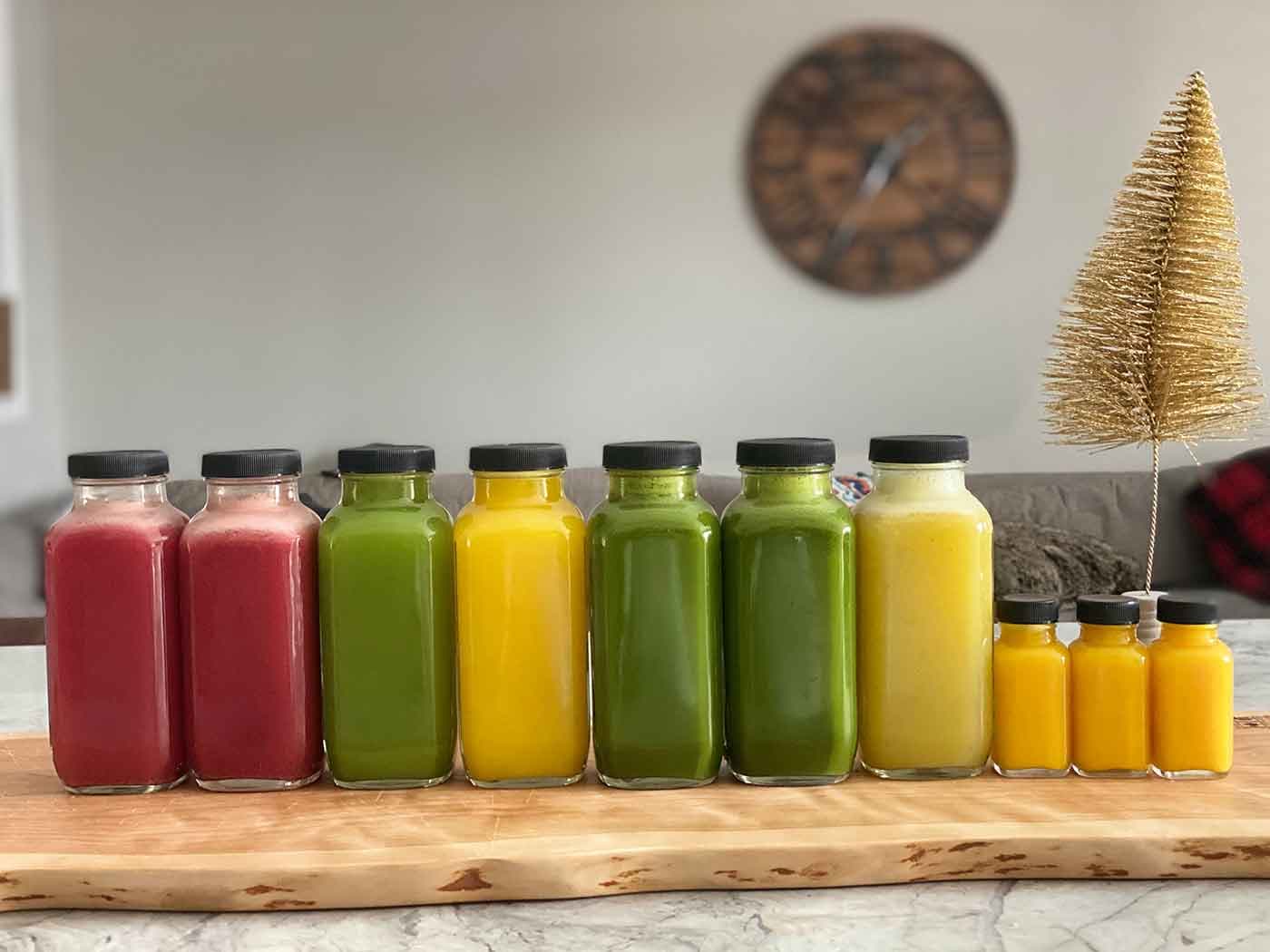 A row of bottled red, green and yellow juices on a wooden board